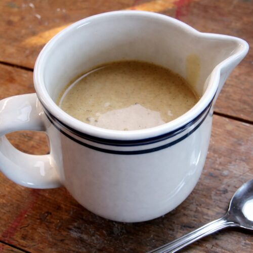 Vanilla Custard Sauce (Vegan, Gluten-free) 3 Cremige vegane Vanillesoße in weißem Kännchen auf rustikalem Holztisch