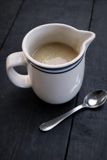 Hausgemachte Vanillesoße vegan serviert im weißen Kännchen