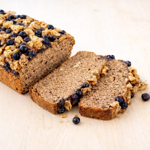 Serviertes Stück Bananenbrot mit Blaubeeren und Walnüssen – vegan & glutenfrei, perfekt zum Frühstück oder Snack.