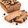 Angeschnittenes veganes Bananenbrot ohne Gluten mit Blaubeeren und Walnüssen auf weißem Untergrund
