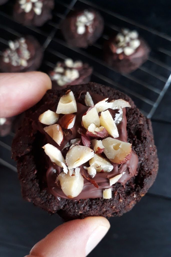 Close-up of finished glazed and decorated vegan and gluten-free triple chocolate cookies with hazelnuts.